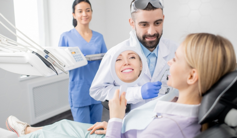 Hình ảnh này chưa có thuộc tính alt; tên tệp của nó là young-smiling-woman-looking-mirror-after-procedure-professional-whitening-while-sitting-armchair-dentist-office.jpg